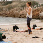 Instructing bridge pose during beach yoga